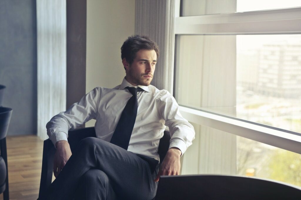 white male professional wearing shirt and tie staring out a window