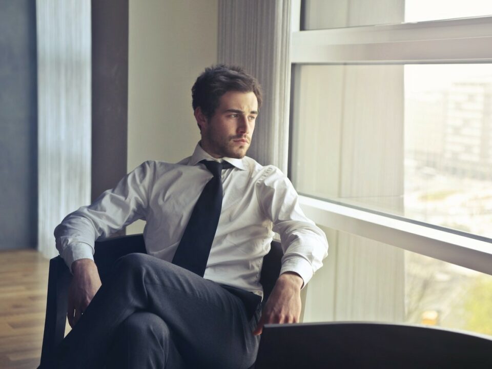 white male professional wearing shirt and tie staring out a window