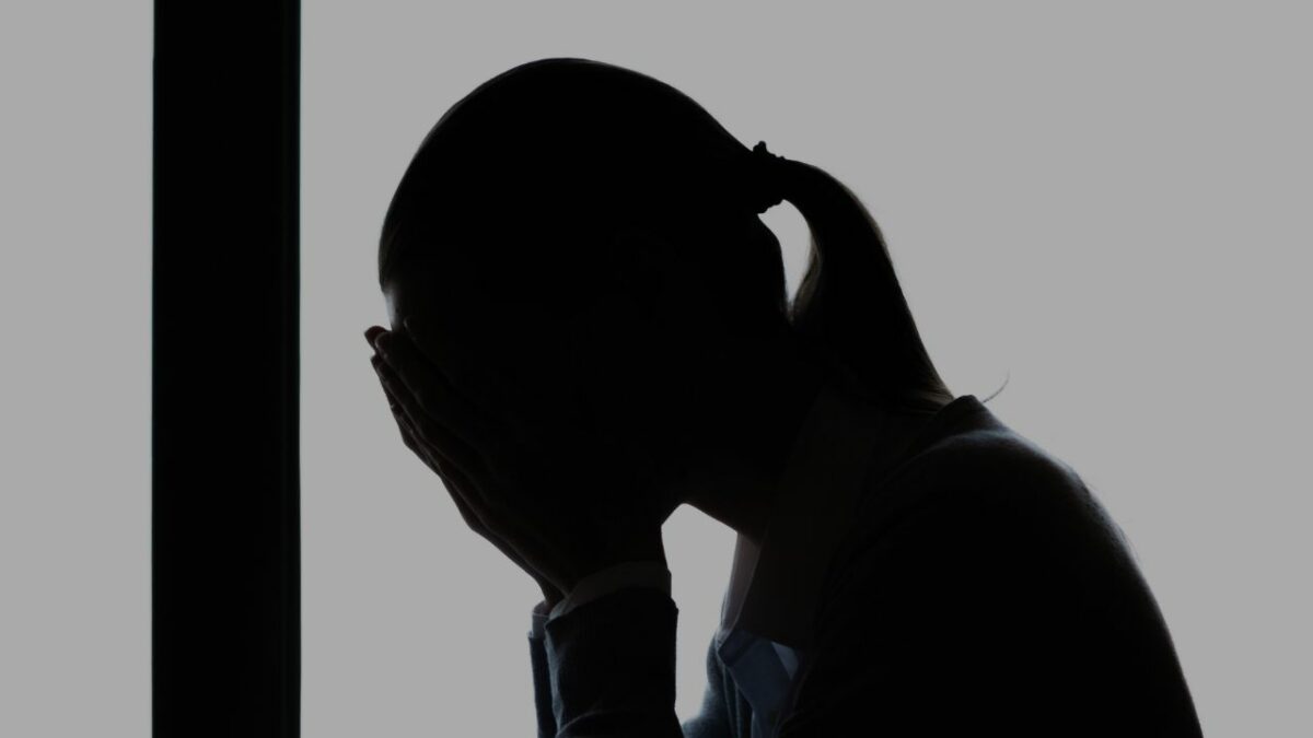 woman with face in hands after sexual harassment at work
